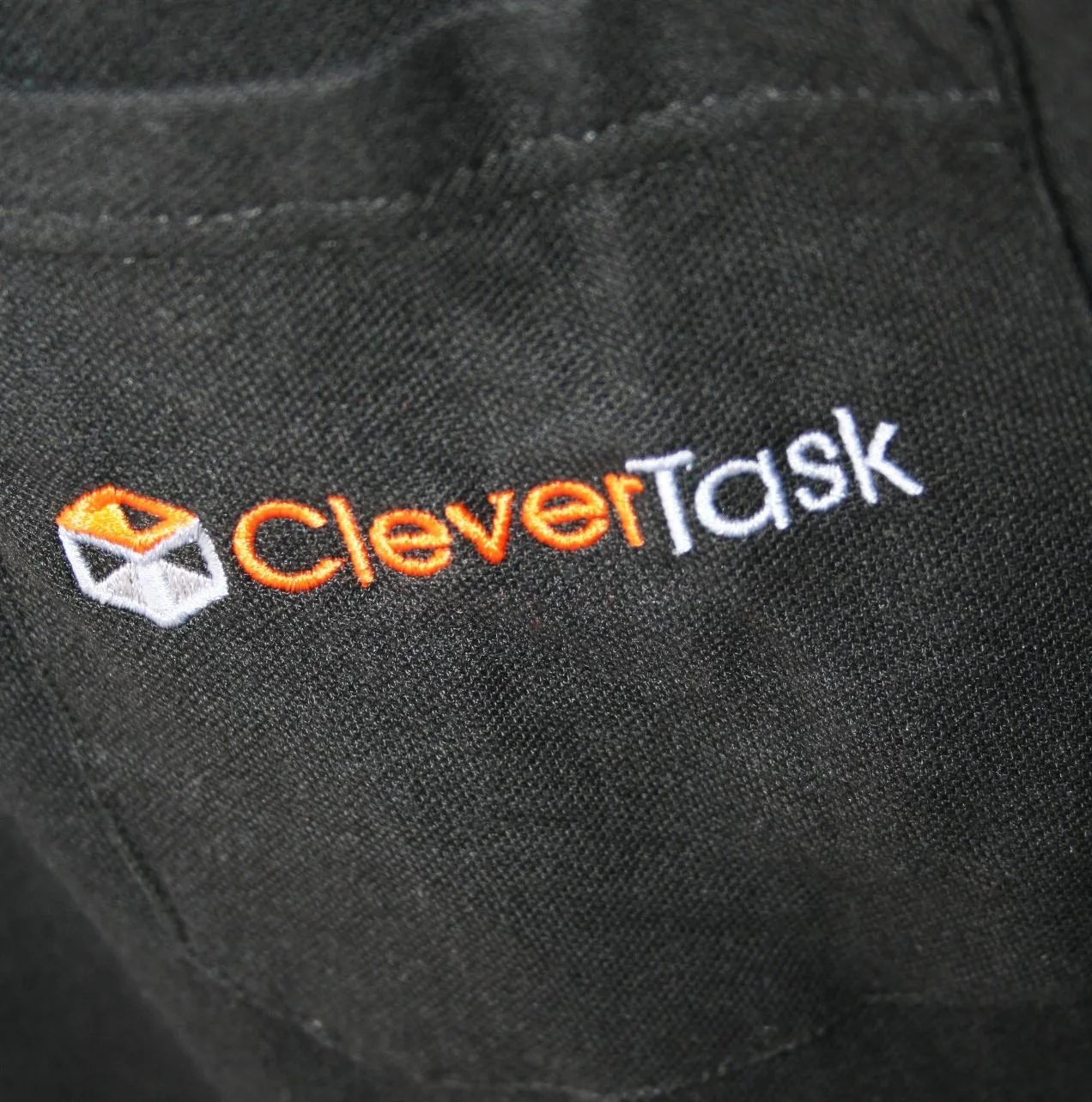 Close-up of an embroidered company logo on a black polo shirt